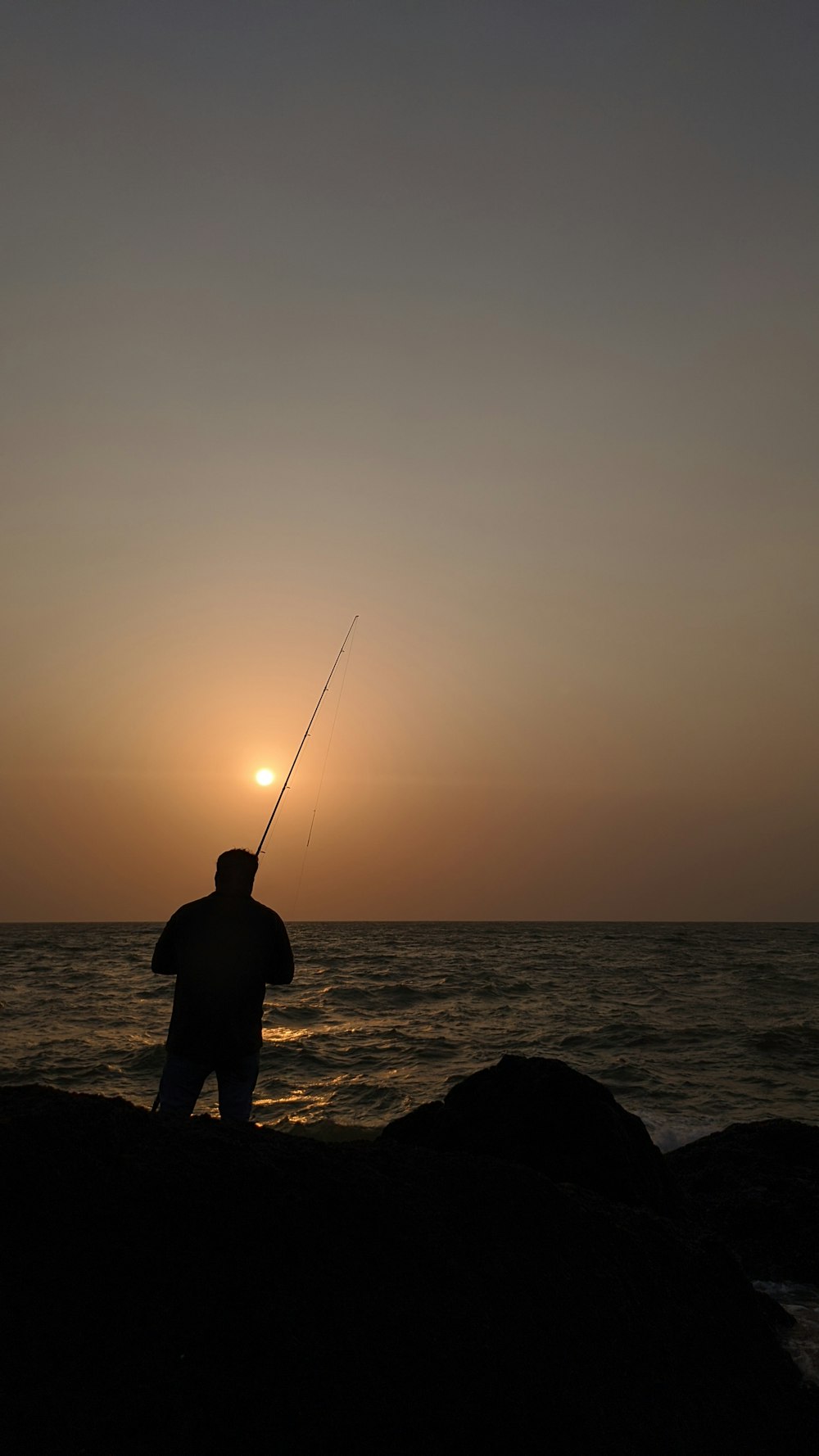 a man standing on top of a rock next to the ocean