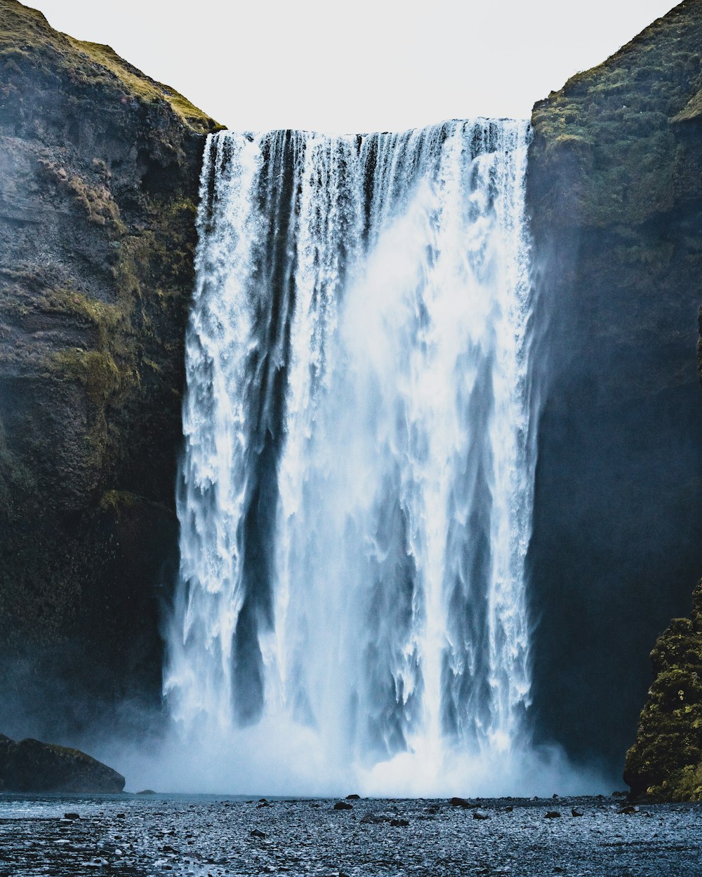 a large waterfall with a man standing in front of it