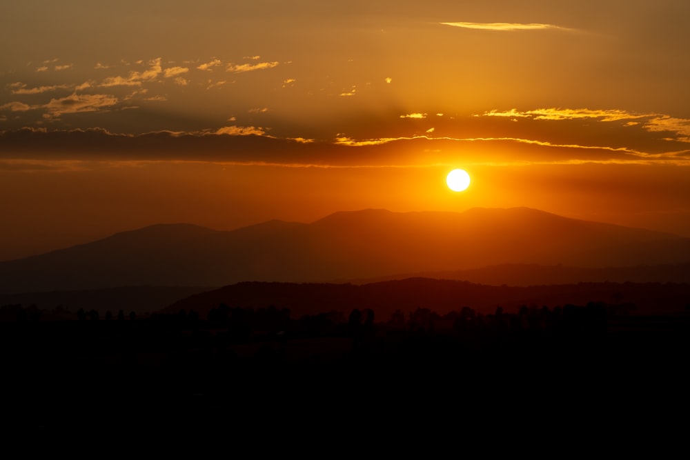 the sun is setting over a mountain range