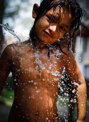 A candid shot of a child playing in a puddle, water droplets frozen mid-air in sharp focus.