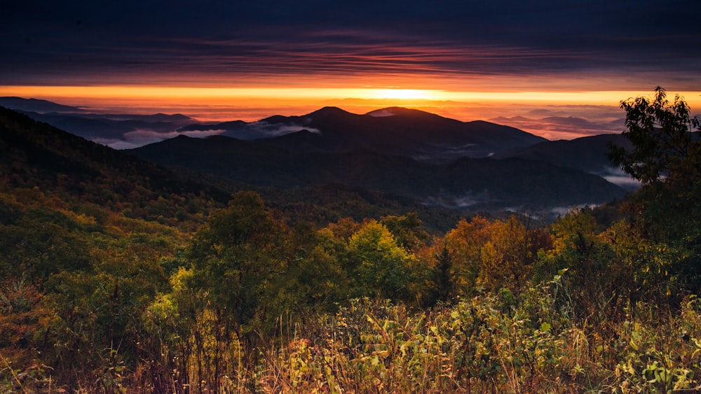 the sun is setting over a mountain range