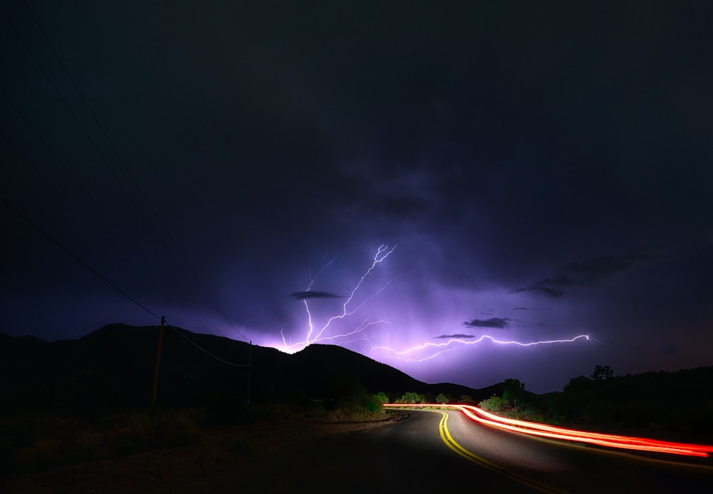 a lightning storm is seen over a highway