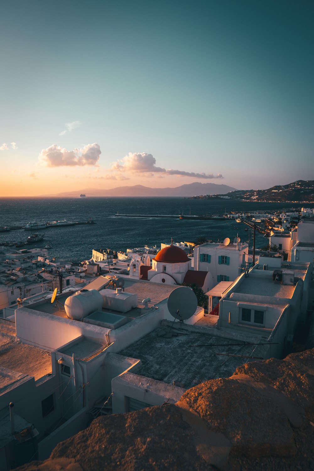 a sunset view of a town with a body of water in the background