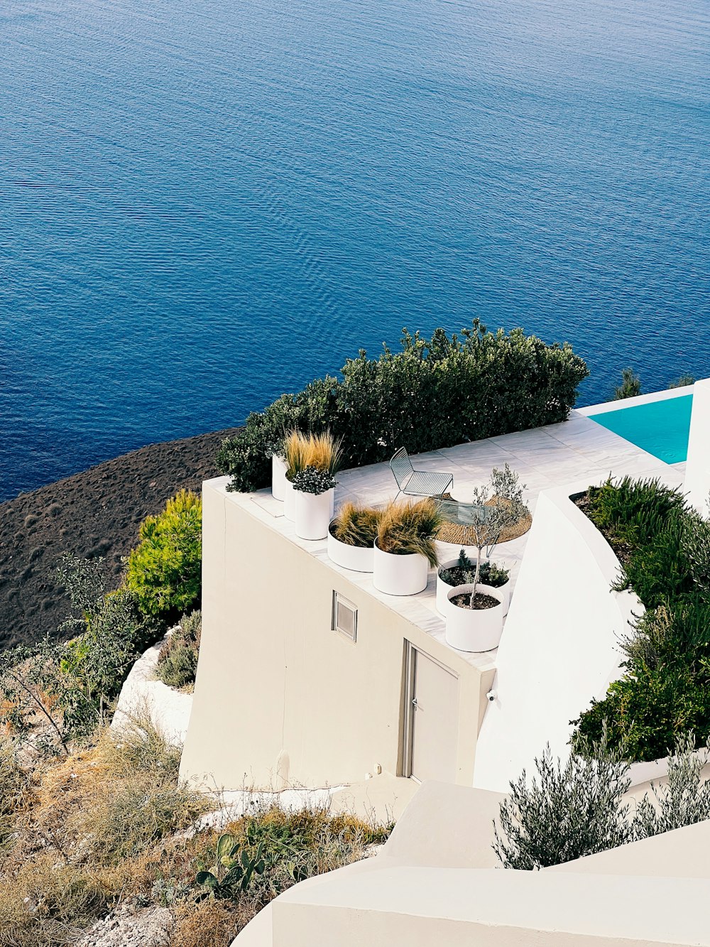 a white house with a pool and plants on the roof