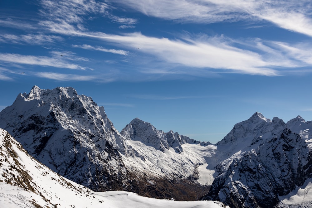 a group of mountains covered in snow under a blue sky