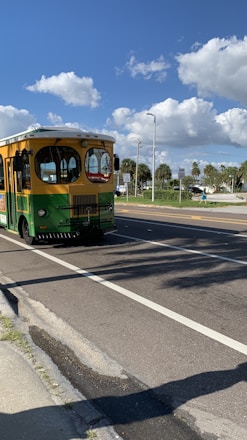 A cheerful shuttle bus parked near a sunny Florida beach with palm trees and clear blue skies.