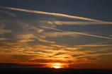 a sunset with contrails in the sky