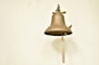 a bell hanging on a wall with a rope