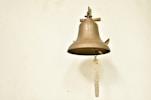 a bell hanging on a wall with a rope