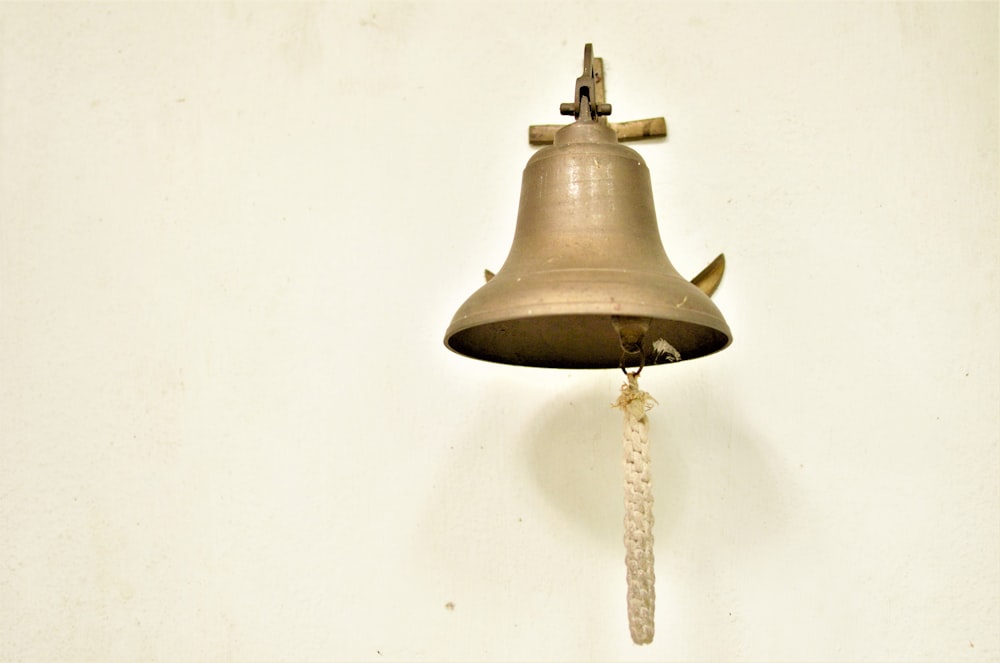 une cloche accrochée à un mur avec une corde