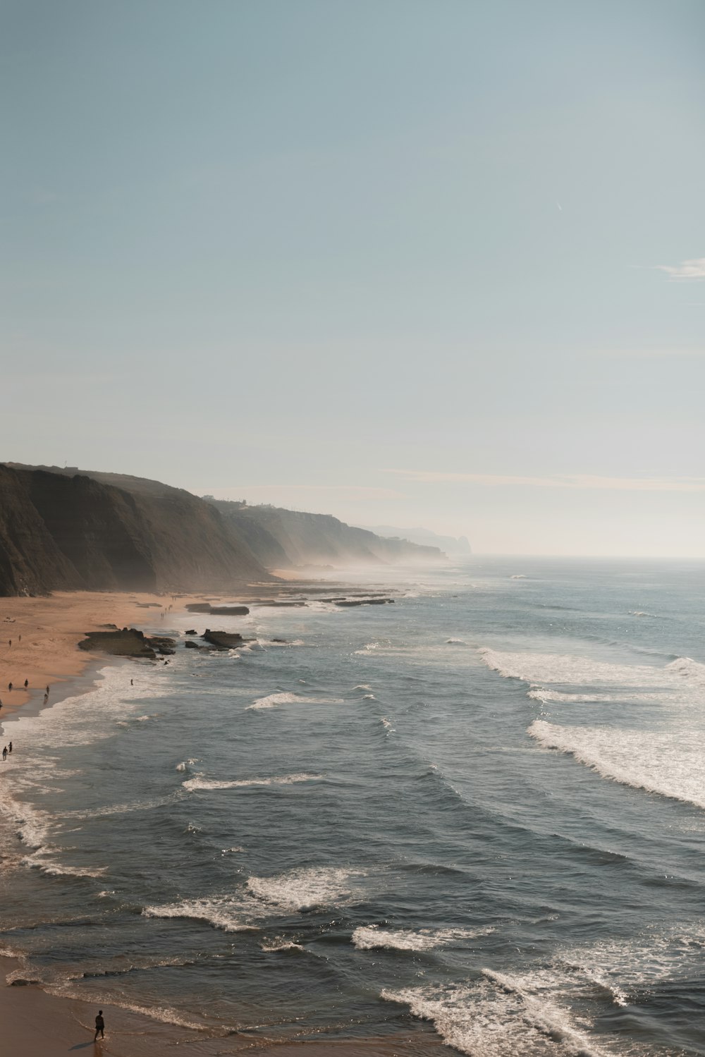 Un groupe de personnes debout au sommet d’une plage au bord de l’océan