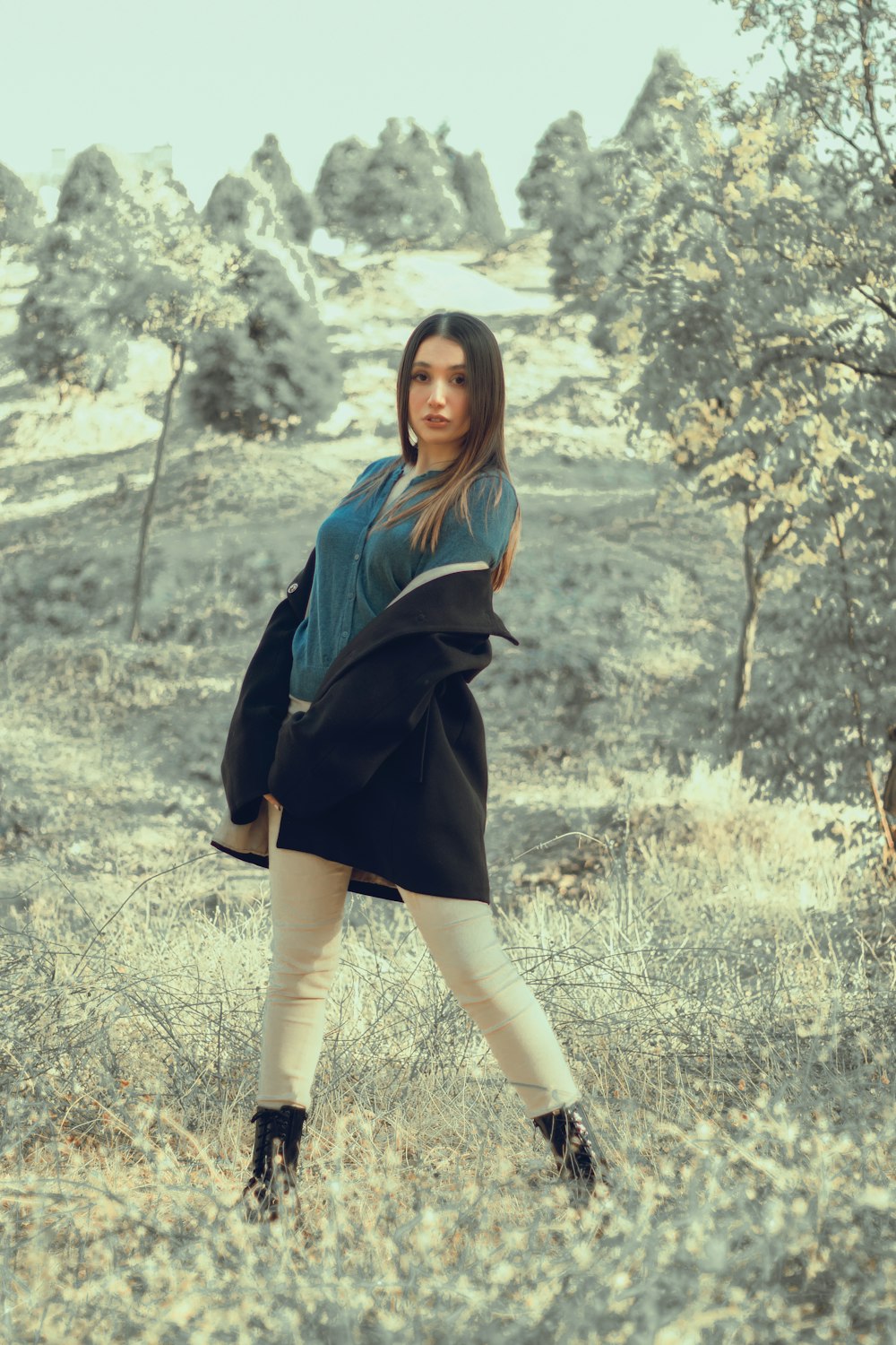 a woman standing in a field with trees in the background