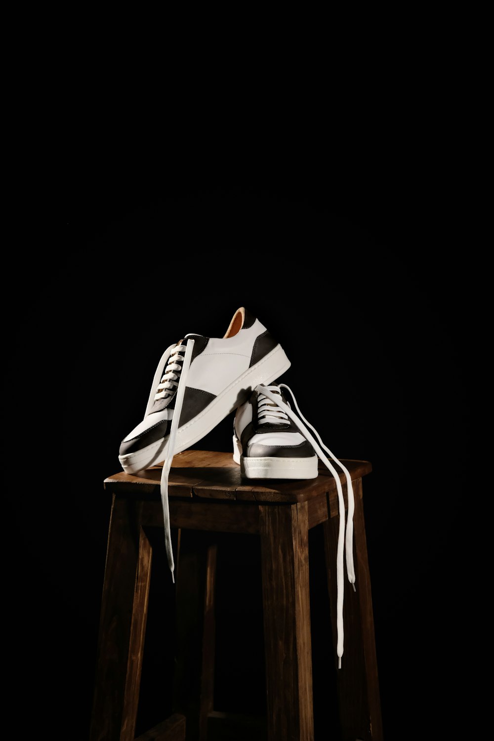 a pair of white shoes sitting on top of a wooden stool
