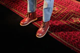 a person standing on a rug wearing red shoes