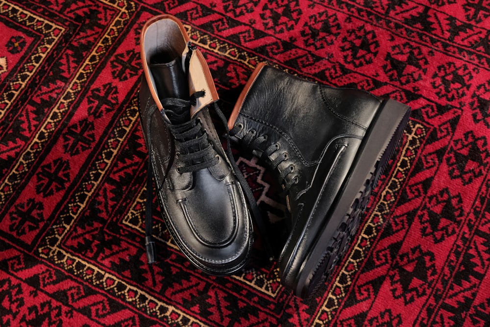 a pair of black shoes sitting on top of a rug