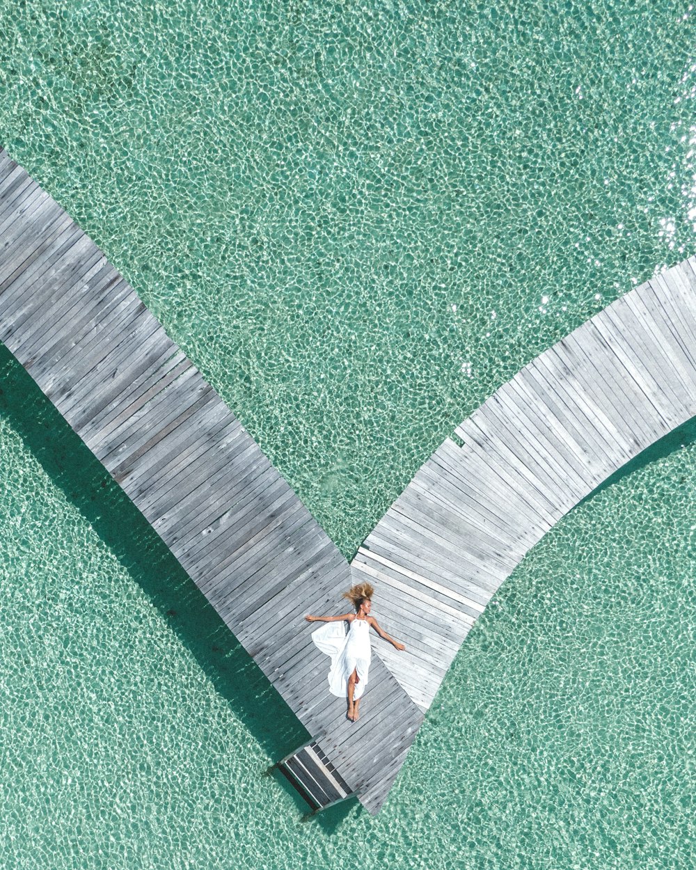 a woman in a white dress standing on a dock