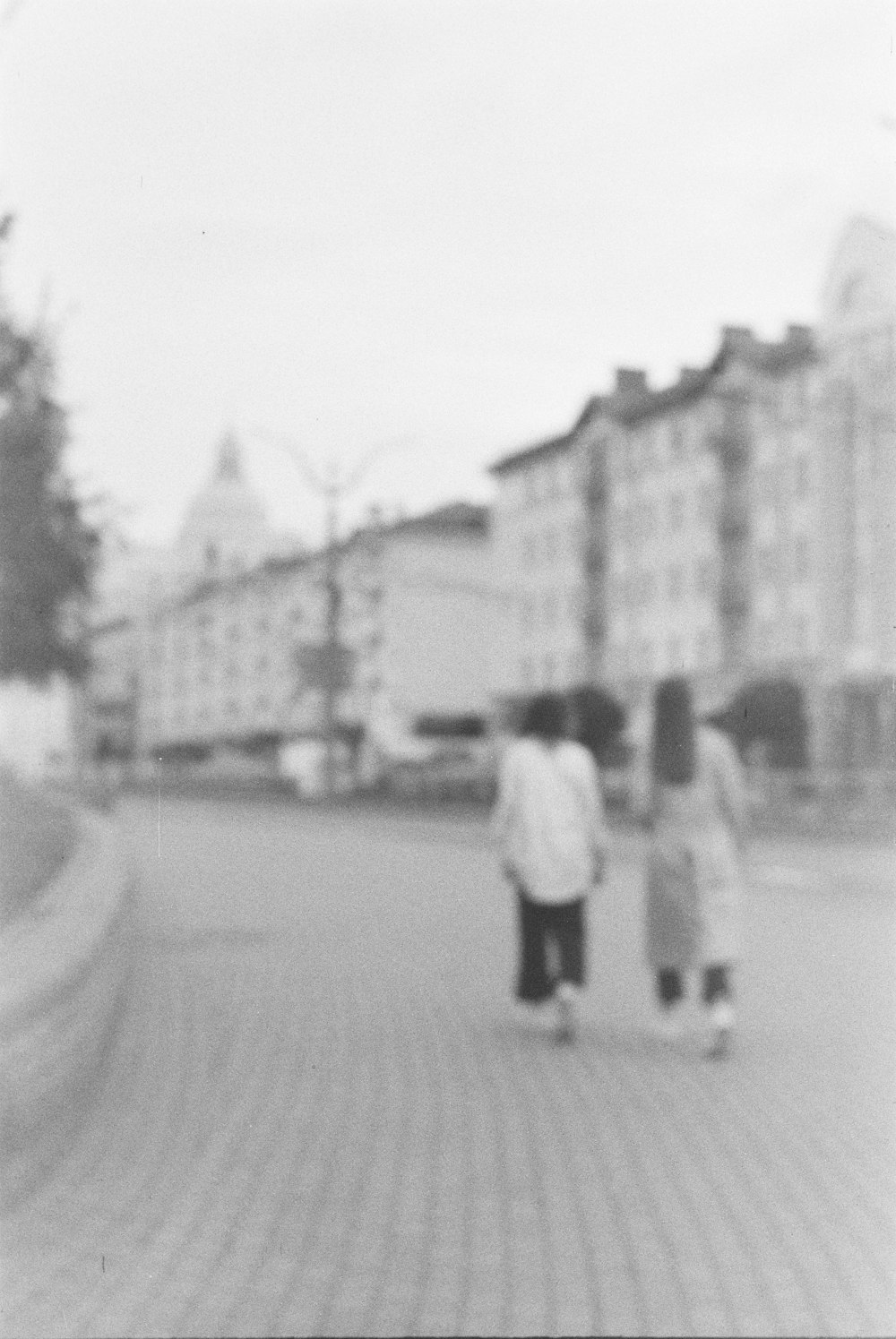 uma foto em preto e branco de três pessoas andando por uma rua