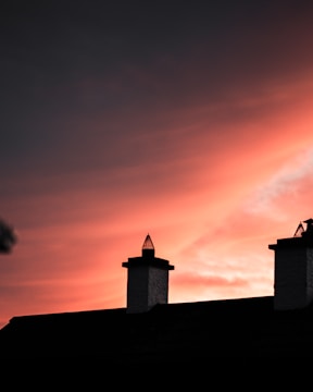 New chimney cap installation on a residential roof at sunset.
