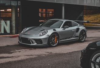 a grey porsche gtr parked in front of a building