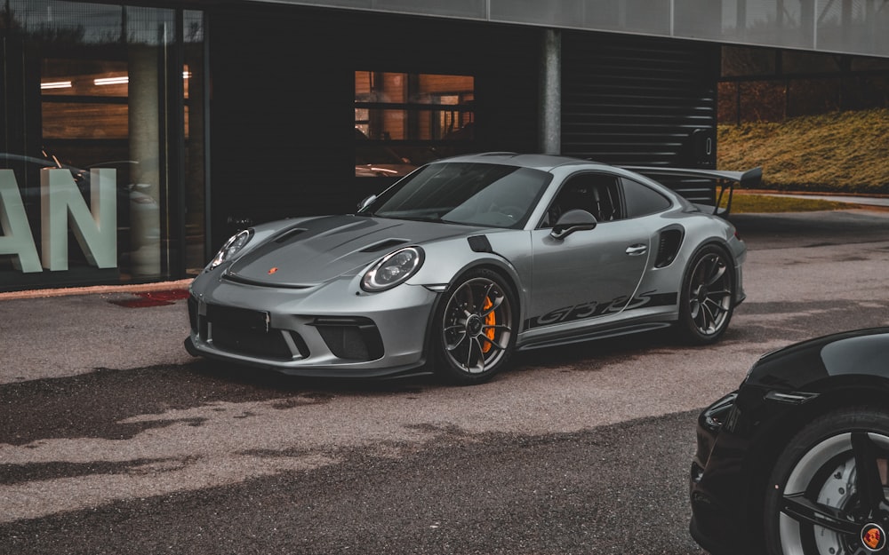 a grey porsche gtr parked in front of a building