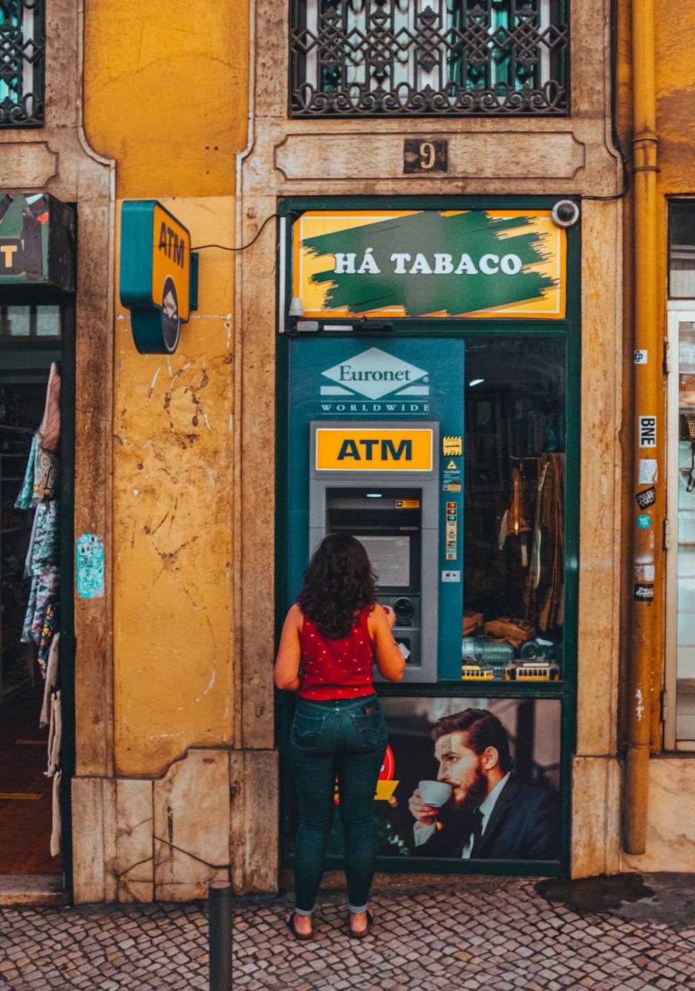 a woman standing in front of a atm machine