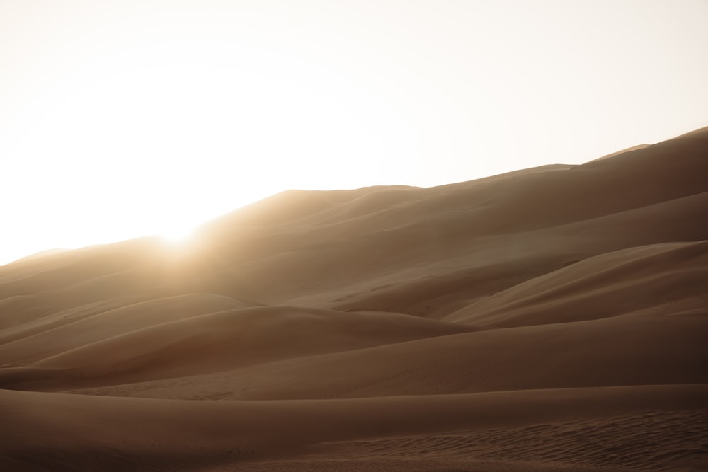 the sun is setting over the sand dunes