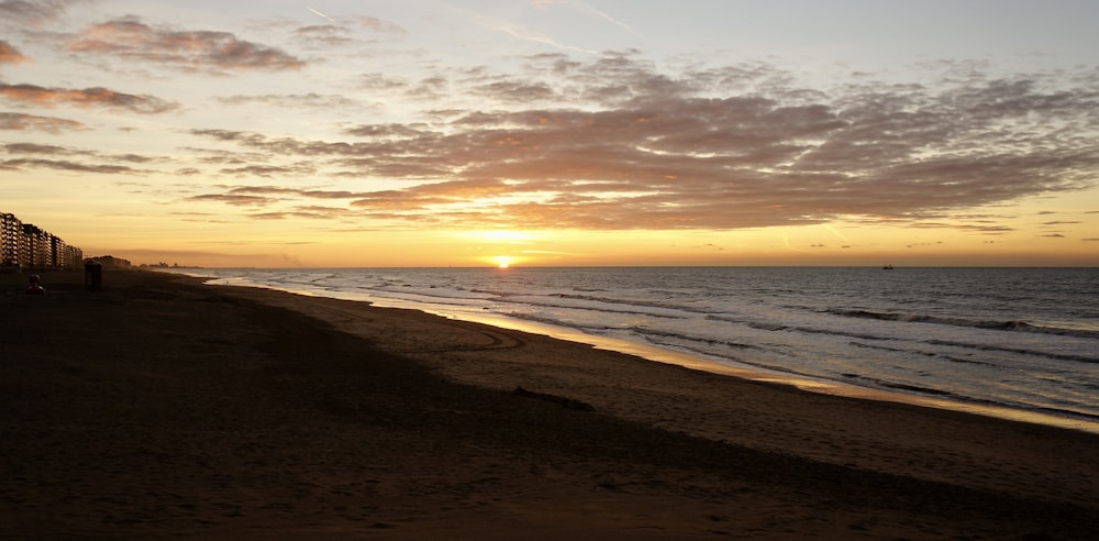 the sun is setting over the ocean on the beach