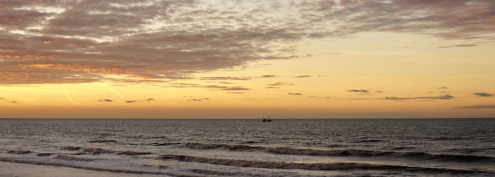 a boat is out on the ocean at sunset