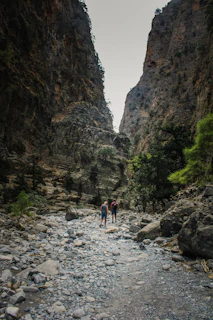 a couple of people standing on a rocky river