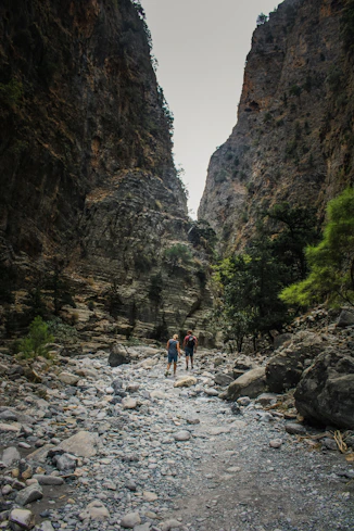 a couple of people standing on a rocky river