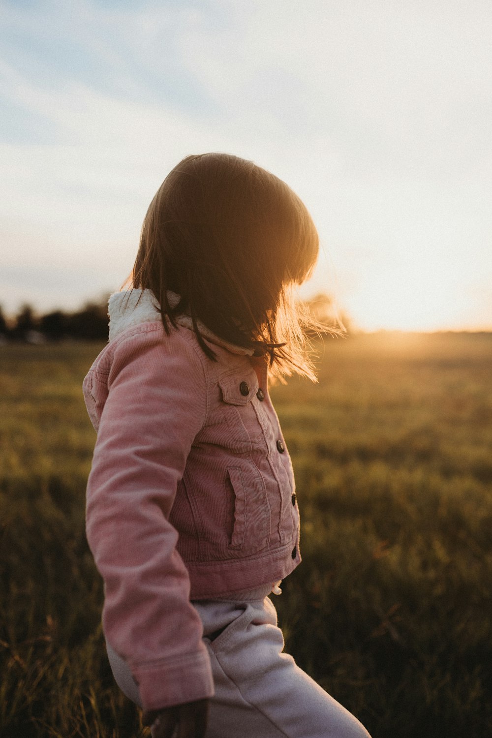a little girl standing in a field of grass