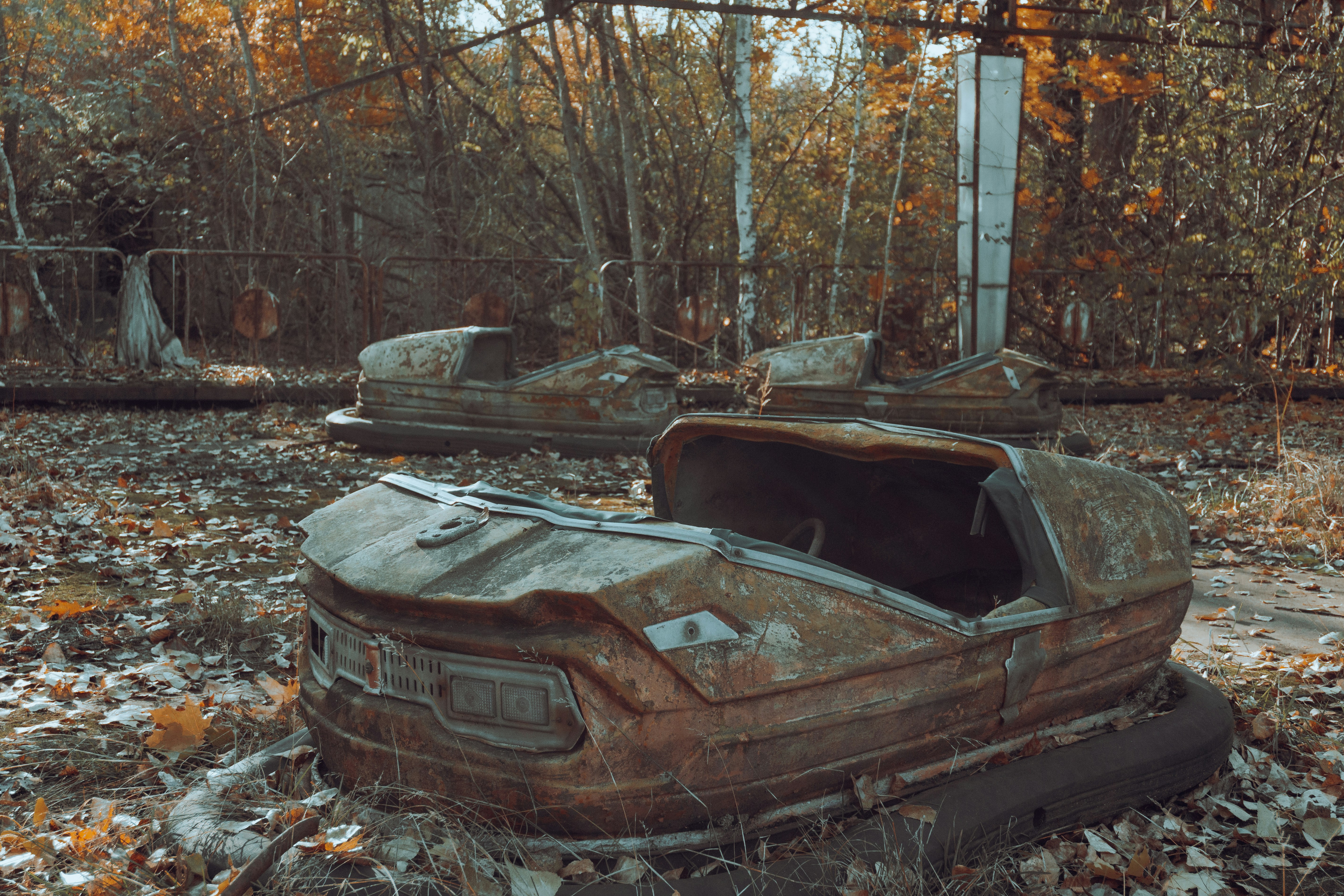 a rusted out car sitting in the middle of a forest