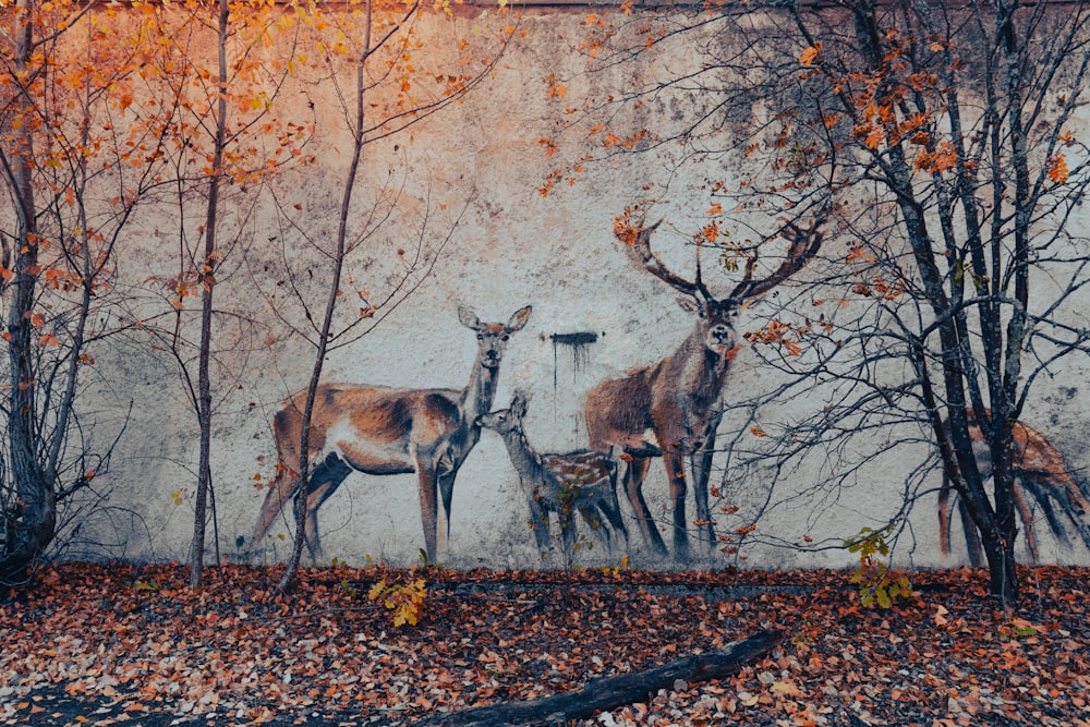 a painting of three deer in front of a wall