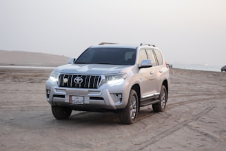 a silver suv parked on a sandy beach
