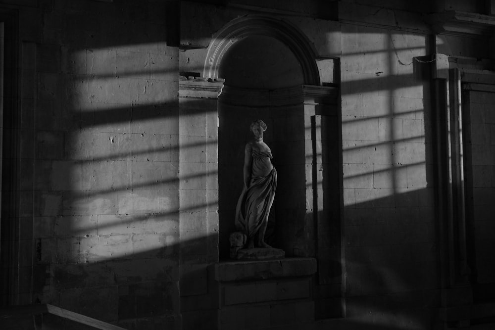 a black and white photo of a statue in a building