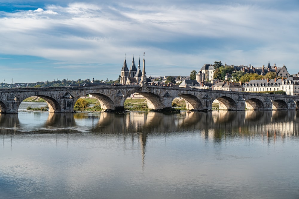 a bridge over a body of water with buildings in the background