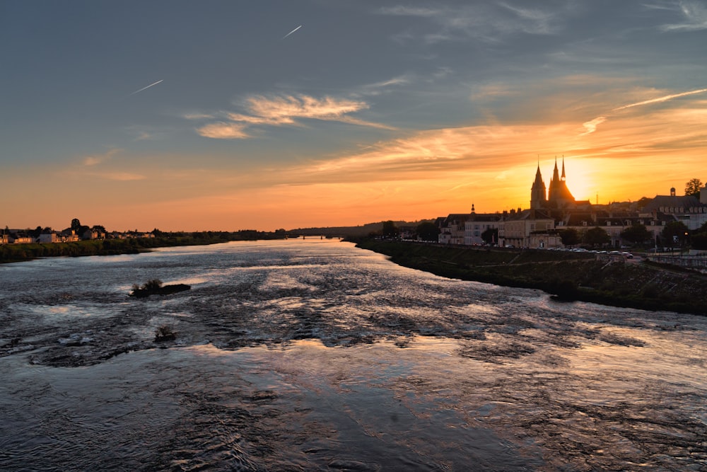 the sun is setting over a river in a city