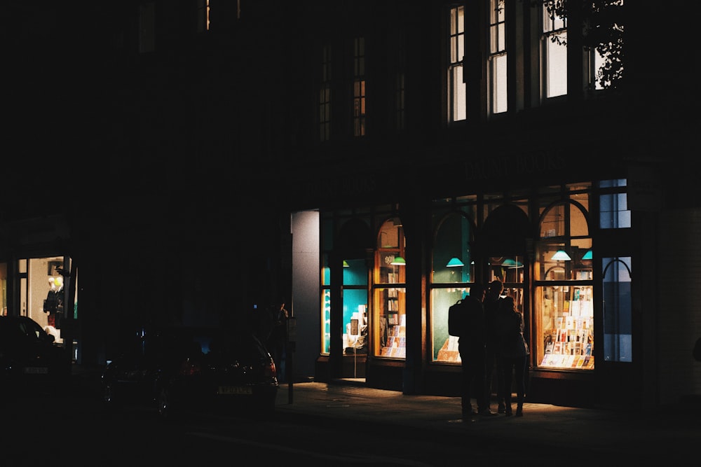 two people standing outside of a building at night