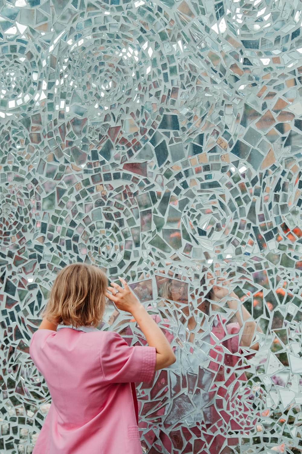 a woman standing in front of a wall made of mirrors