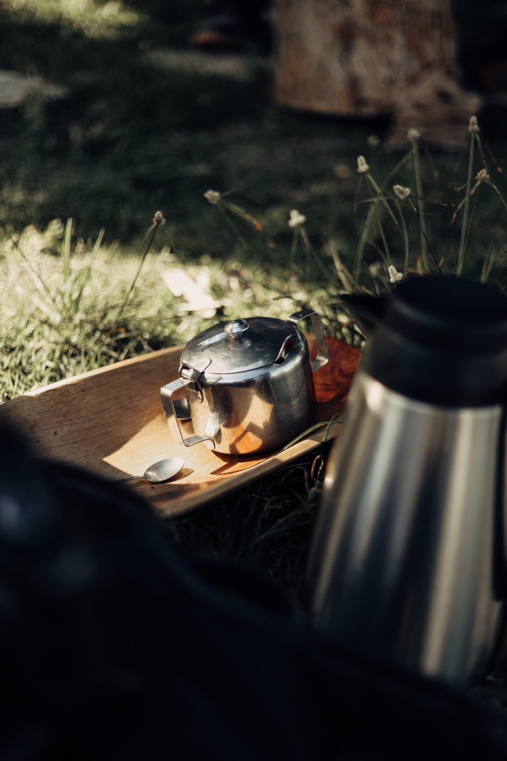 a metal tea pot sitting on top of a wooden tray