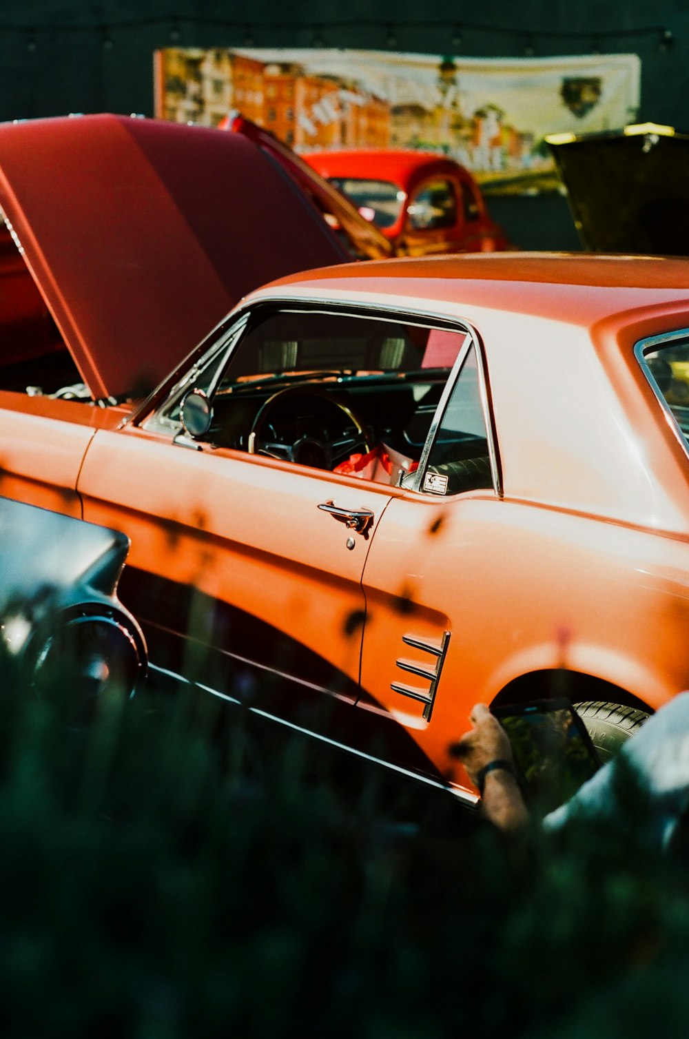 Un coche naranja aparcado junto a otros coches antiguos