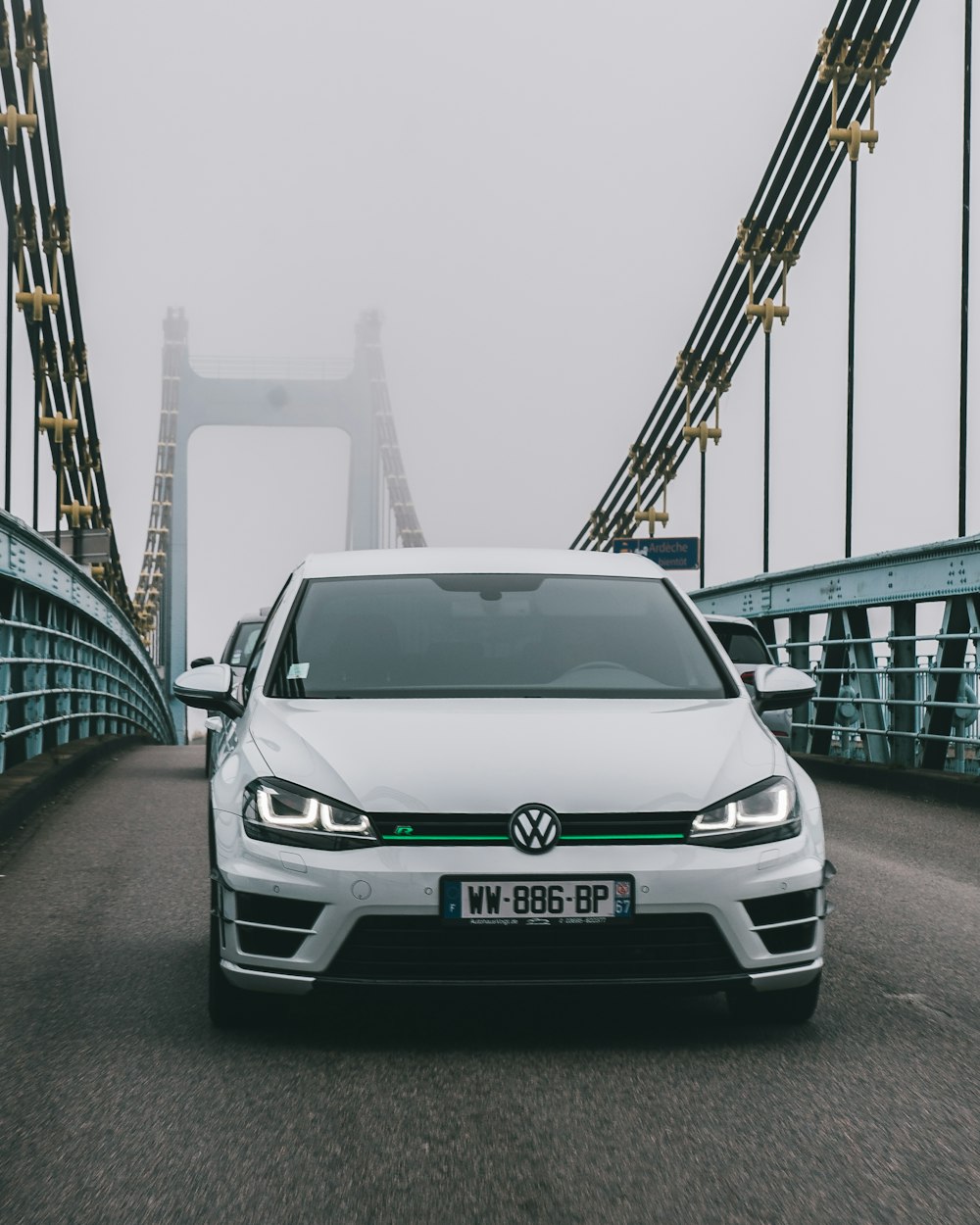 a white car driving across a bridge on a foggy day