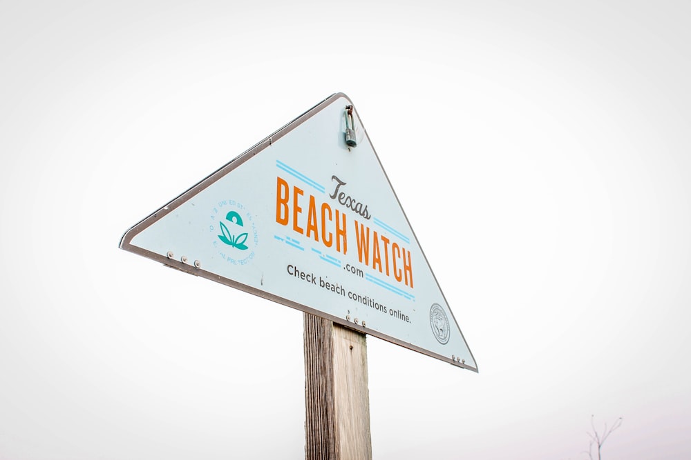 Un letrero de reloj de playa en la parte superior de un poste de madera