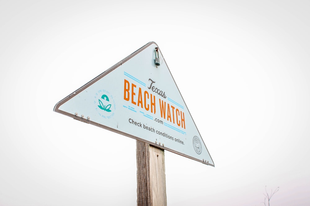 a beach watch sign on top of a wooden pole