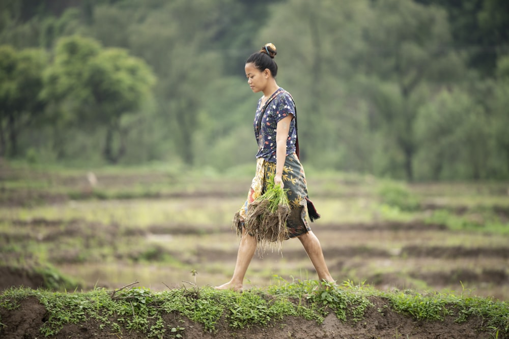 a woman walking across a lush green field