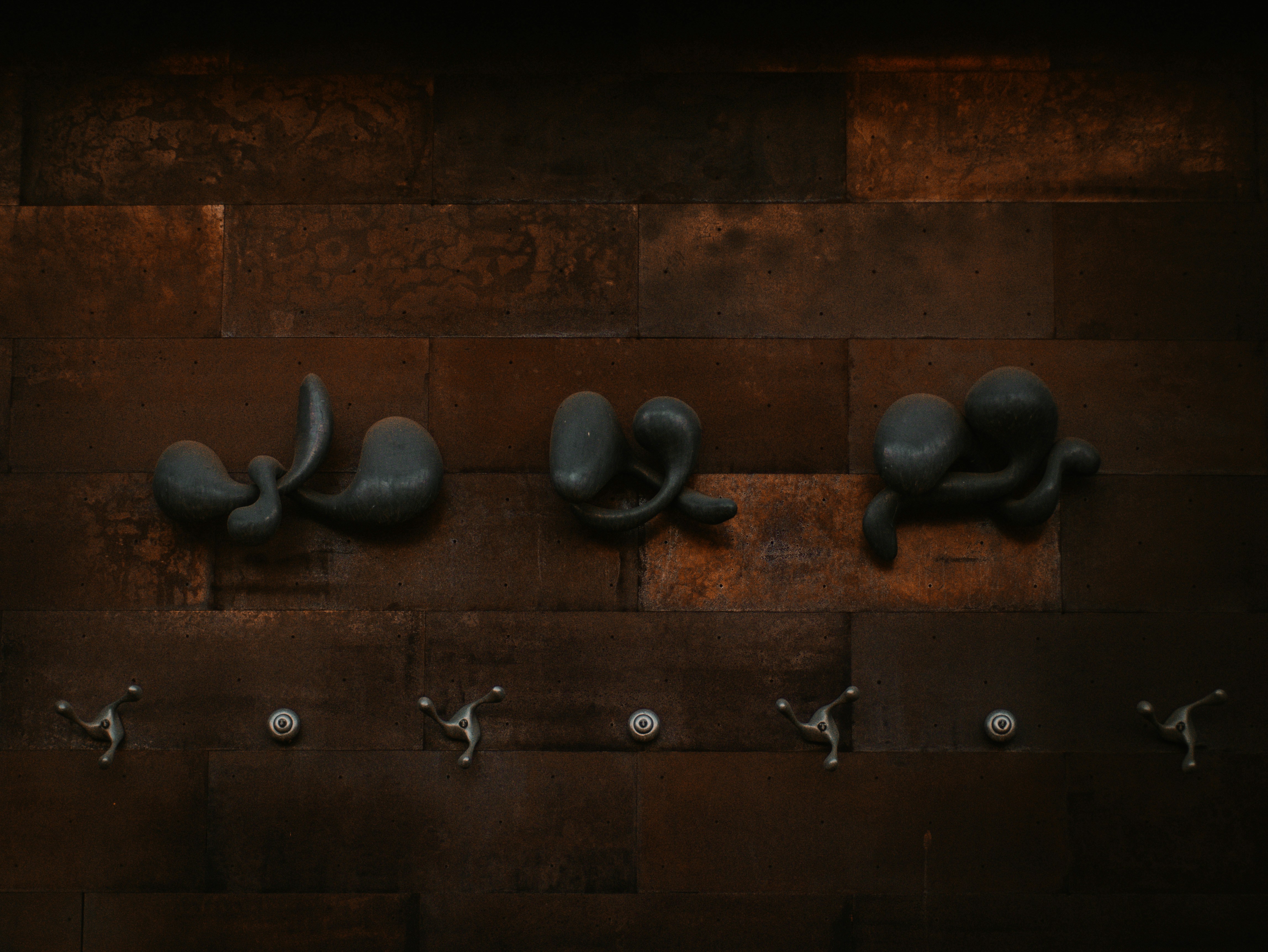a row of metal faucets mounted to a wall