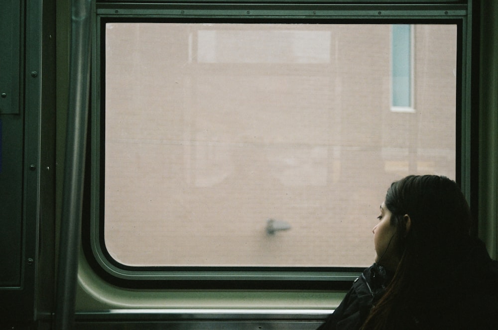 a woman sitting on a train looking out the window