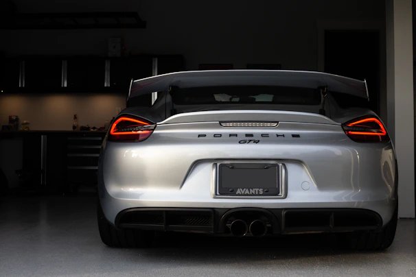 A Porsche sports car parked beside a metallic silver tool cabinet with subtle red accents in the background.