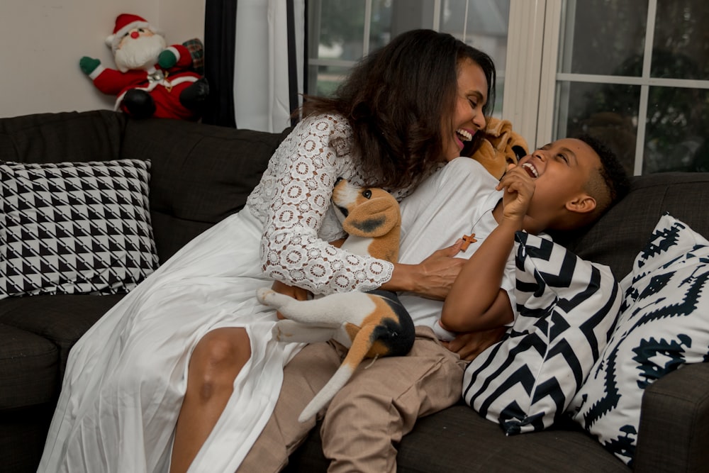 a woman and a boy sitting on a couch with stuffed animals