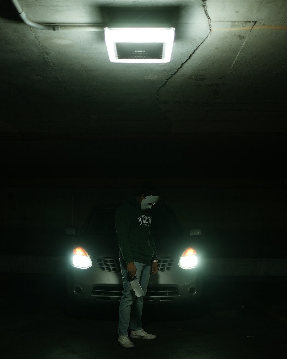 a man standing in a parking garage next to a car